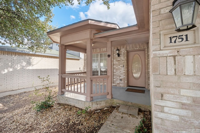 property entrance with brick siding and a porch