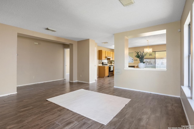 unfurnished living room featuring a notable chandelier, visible vents, dark wood-type flooring, a textured ceiling, and baseboards