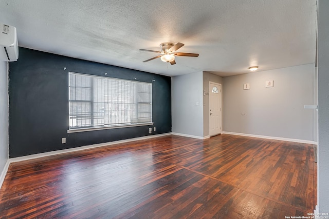 spare room with a wall mounted AC, wood finished floors, and baseboards