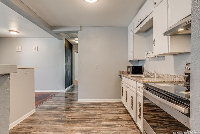 kitchen with under cabinet range hood, dark wood-style flooring, a sink, baseboards, and electric stove