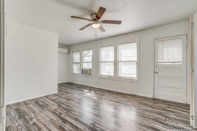 interior space with a ceiling fan, cooling unit, wood finished floors, and a wall mounted AC