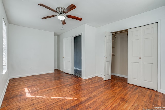 unfurnished bedroom with a closet, wood-type flooring, ceiling fan, and baseboards