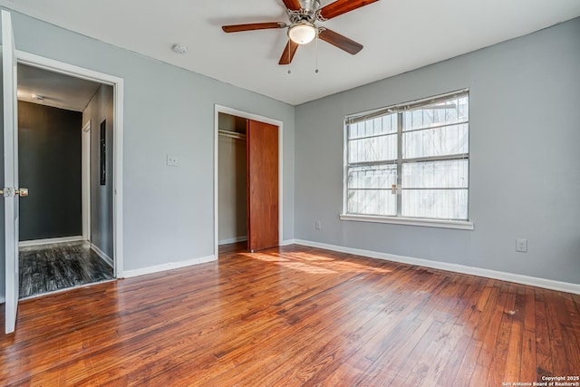 unfurnished bedroom featuring ceiling fan, a closet, wood-type flooring, and baseboards