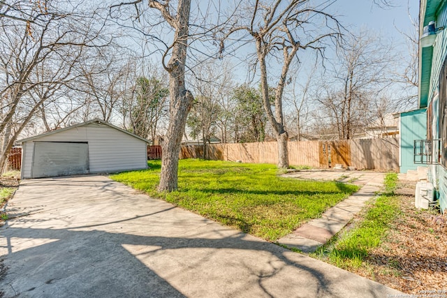 view of yard with a garage, driveway, an outdoor structure, and fence