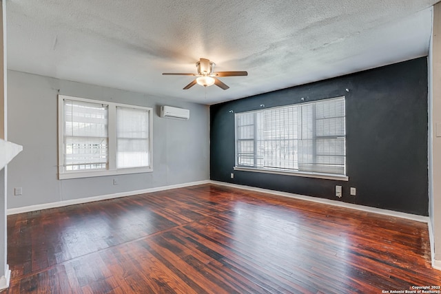 empty room with a wall mounted AC, wood-type flooring, and a wealth of natural light