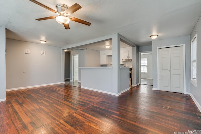 unfurnished living room with a ceiling fan, dark wood-style flooring, and baseboards