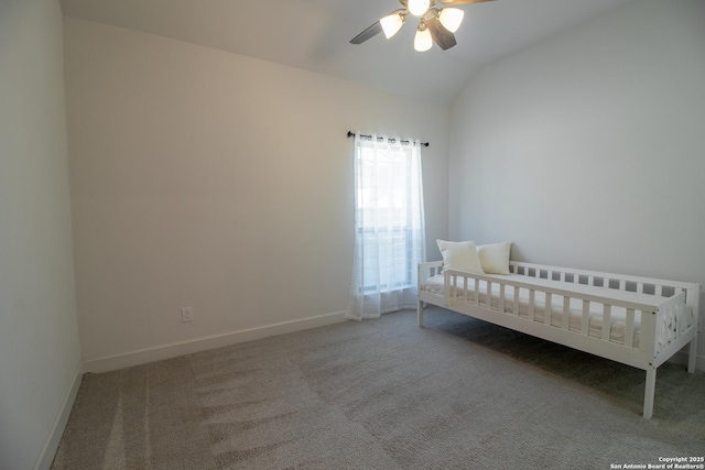 unfurnished bedroom featuring ceiling fan, baseboards, vaulted ceiling, a crib, and carpet