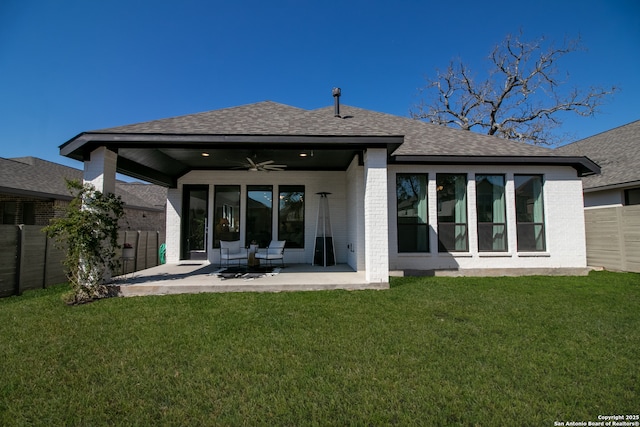 rear view of property with a yard, brick siding, fence, and a ceiling fan