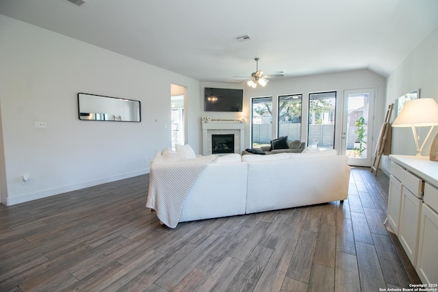 living area featuring a fireplace, visible vents, dark wood-type flooring, a ceiling fan, and baseboards