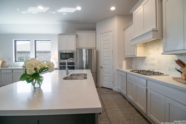 kitchen featuring recessed lighting, decorative backsplash, appliances with stainless steel finishes, a kitchen island with sink, and a sink