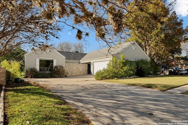 ranch-style house featuring stucco siding, an attached garage, a front yard, stone siding, and driveway