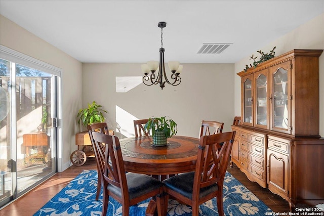 dining space with visible vents, dark wood finished floors, and an inviting chandelier