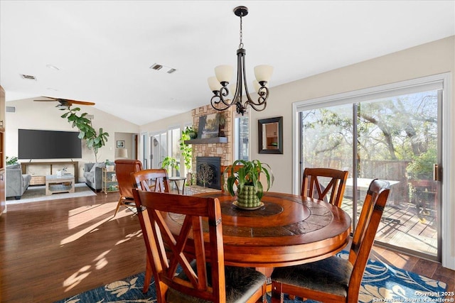 dining area featuring lofted ceiling, a large fireplace, visible vents, and wood finished floors