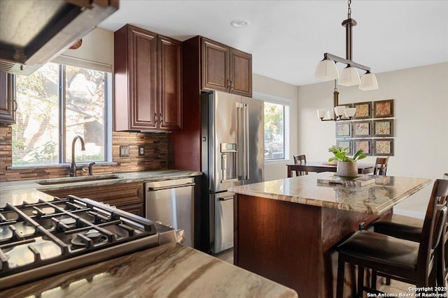 kitchen featuring high quality fridge, a breakfast bar, a sink, backsplash, and dishwasher