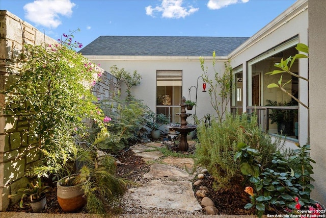 exterior space featuring a shingled roof and stucco siding