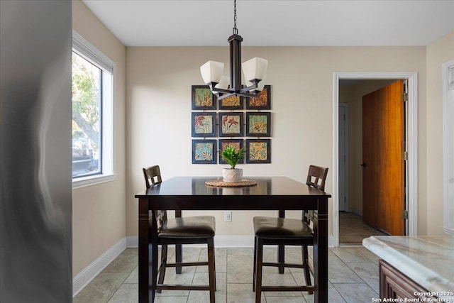 dining area featuring light tile patterned flooring, a notable chandelier, and baseboards