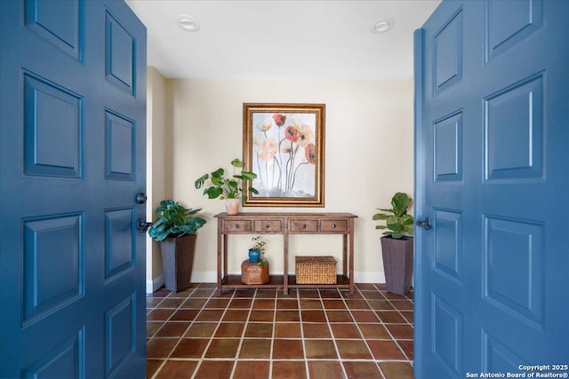 foyer entrance with dark tile patterned flooring and baseboards