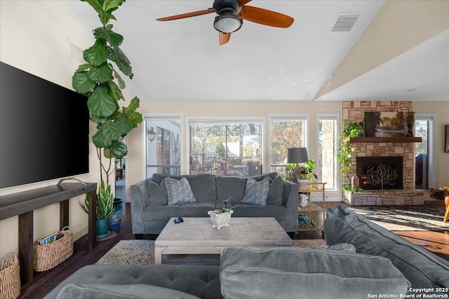 living area with lofted ceiling, a fireplace, visible vents, and wood finished floors