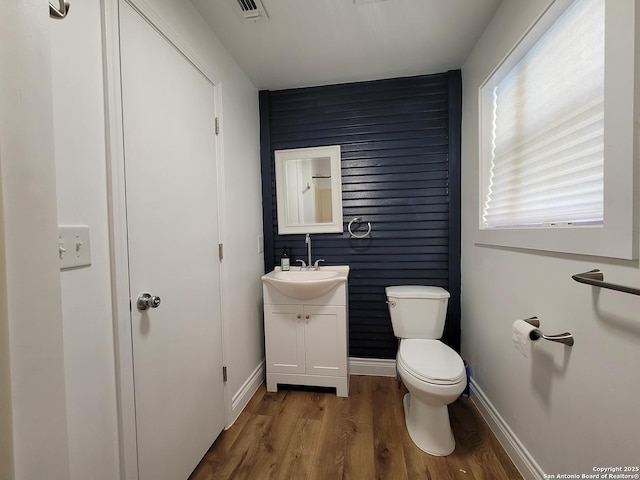 bathroom featuring baseboards, visible vents, toilet, wood finished floors, and vanity