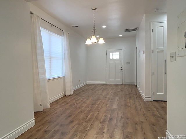 interior space with a notable chandelier, baseboards, visible vents, and wood finished floors