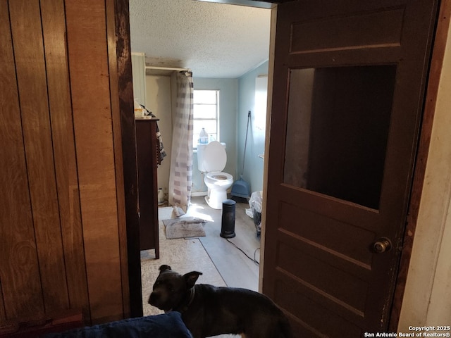 bathroom with a textured ceiling, a shower stall, and toilet