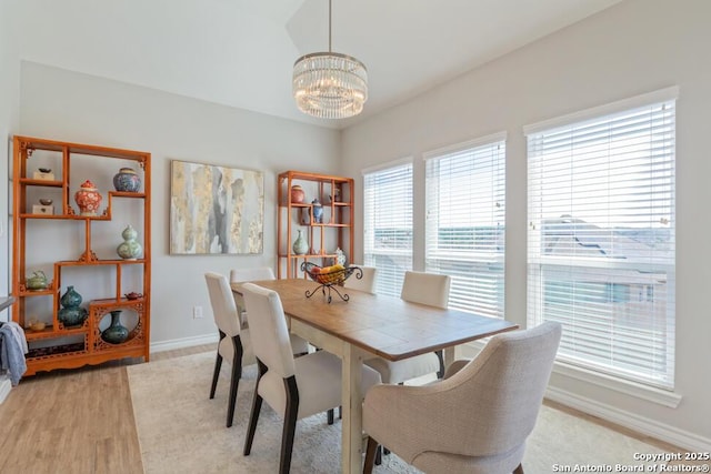 dining room with baseboards, a chandelier, and light wood-style flooring