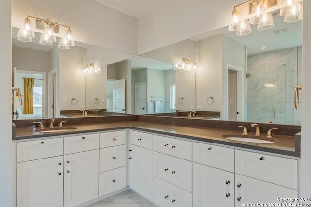 bathroom with double vanity, marble finish floor, a shower stall, and a sink