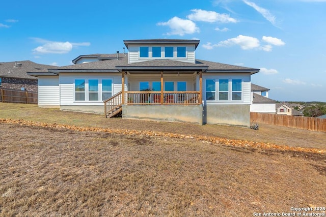 back of house with covered porch, fence, and a lawn