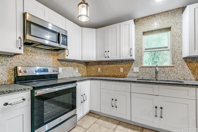 kitchen featuring light tile patterned floors, white cabinets, decorative backsplash, stainless steel appliances, and a sink