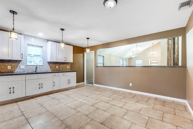 kitchen featuring a sink, visible vents, white cabinets, backsplash, and dark countertops