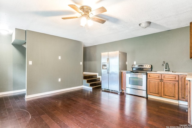 kitchen with a sink, light countertops, appliances with stainless steel finishes, brown cabinetry, and dark wood finished floors