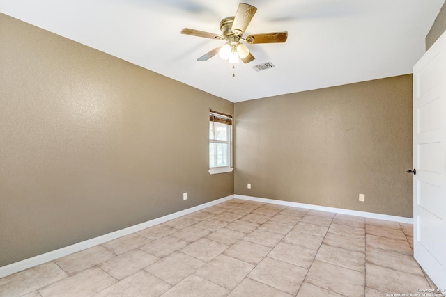 empty room featuring baseboards, light tile patterned floors, visible vents, and a ceiling fan