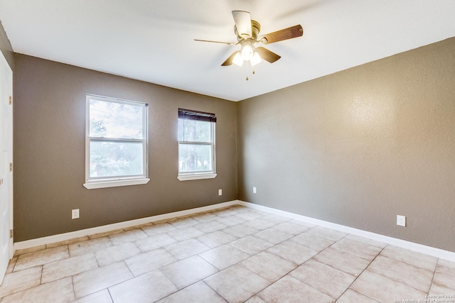 empty room with a ceiling fan and baseboards