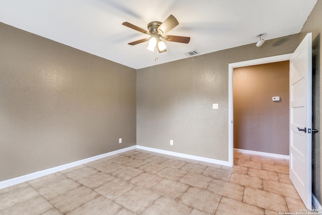 spare room with a textured wall, visible vents, ceiling fan, and baseboards