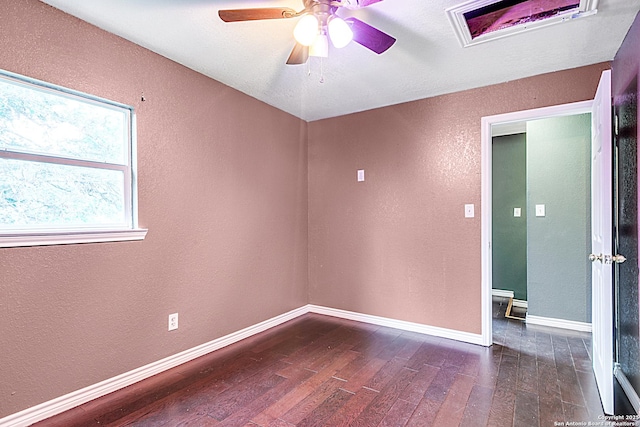 unfurnished room with dark wood-type flooring, a textured wall, baseboards, and a ceiling fan