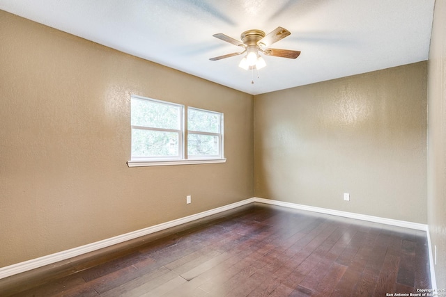 spare room with ceiling fan, dark wood-type flooring, and baseboards