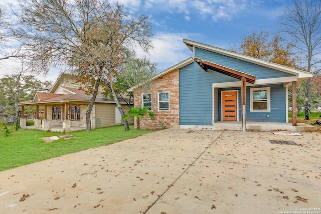 view of front facade featuring covered porch, stone siding, and a front yard