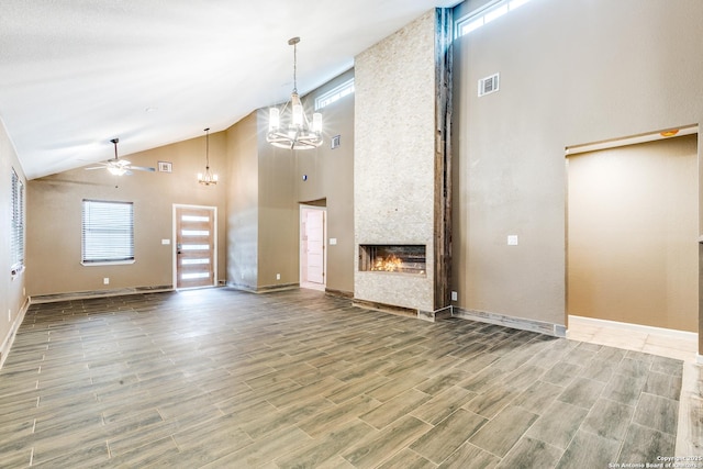 unfurnished living room featuring high vaulted ceiling, ceiling fan with notable chandelier, a fireplace, visible vents, and wood tiled floor