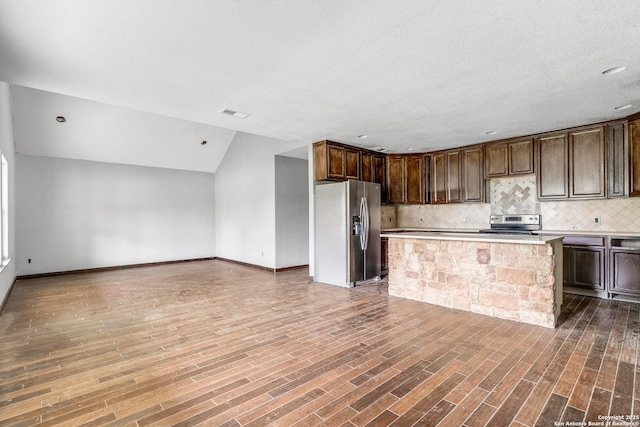 kitchen featuring stainless steel appliances, wood finished floors, light countertops, and tasteful backsplash