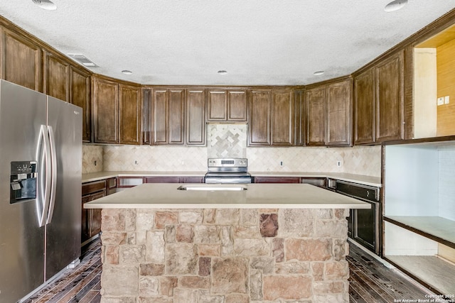 kitchen with a center island with sink, stainless steel appliances, light countertops, visible vents, and a textured ceiling