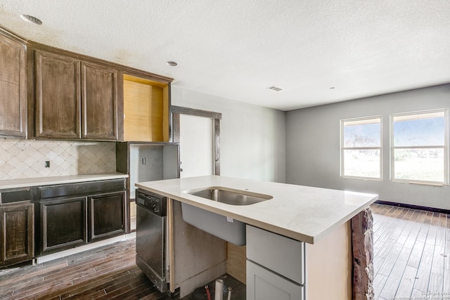 kitchen with dark wood-style floors, decorative backsplash, light countertops, and dishwasher