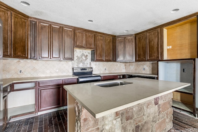 kitchen featuring dark wood finished floors, a sink, a textured ceiling, stainless steel range with electric stovetop, and backsplash