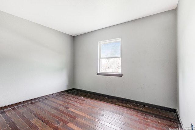 unfurnished room with baseboards and dark wood-style flooring