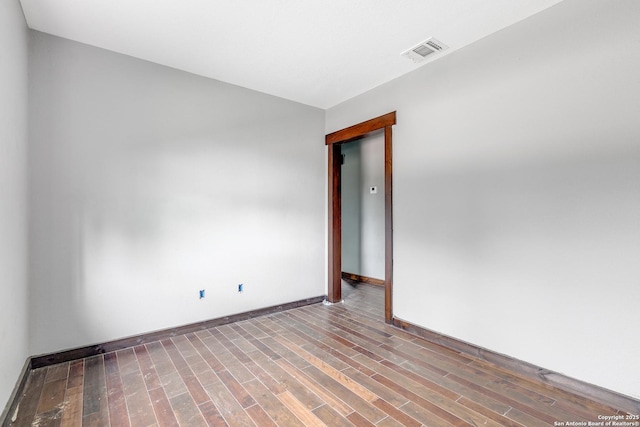 unfurnished room with baseboards, visible vents, and wood finished floors