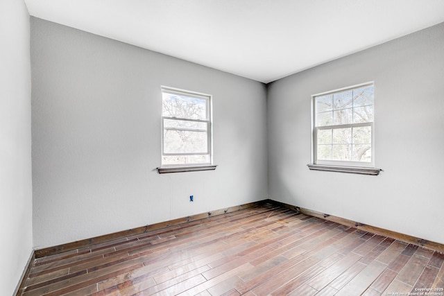 unfurnished room with a healthy amount of sunlight, baseboards, and wood finished floors