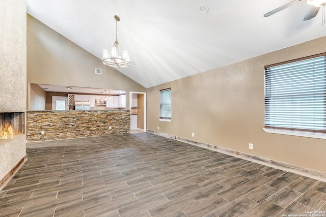 unfurnished living room featuring ceiling fan with notable chandelier, high vaulted ceiling, visible vents, and wood tiled floor