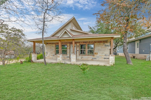 rear view of house with stone siding, a shingled roof, and a lawn