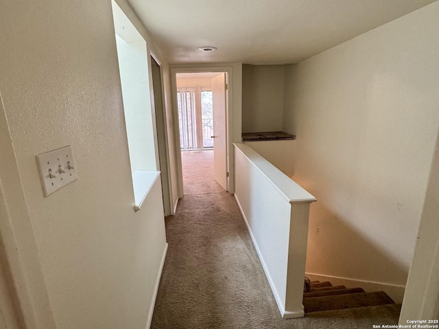 hallway with baseboards, light colored carpet, and an upstairs landing