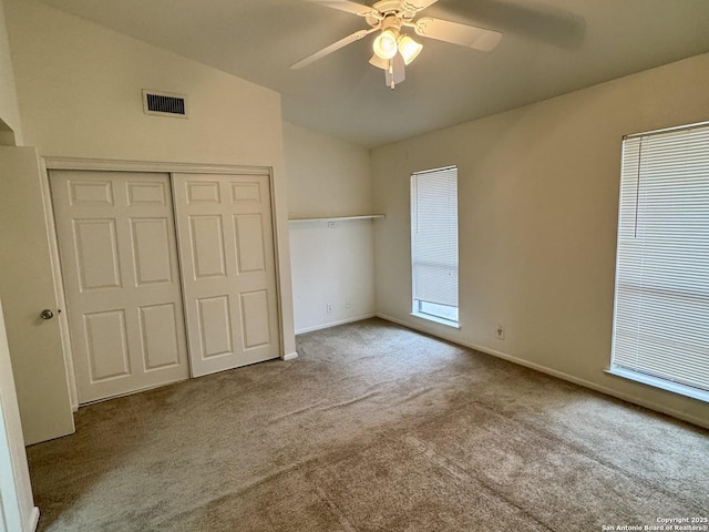 unfurnished bedroom with visible vents, ceiling fan, carpet, vaulted ceiling, and a closet