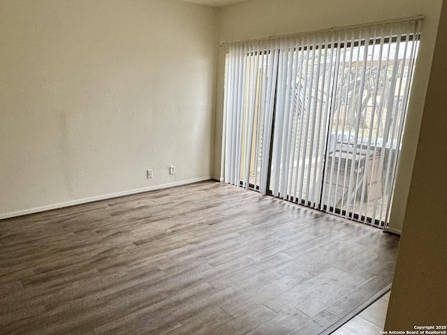 spare room with baseboards and wood finished floors